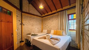 Una habitación con dos camas, una puerta de madera y una pared de ladrillo.