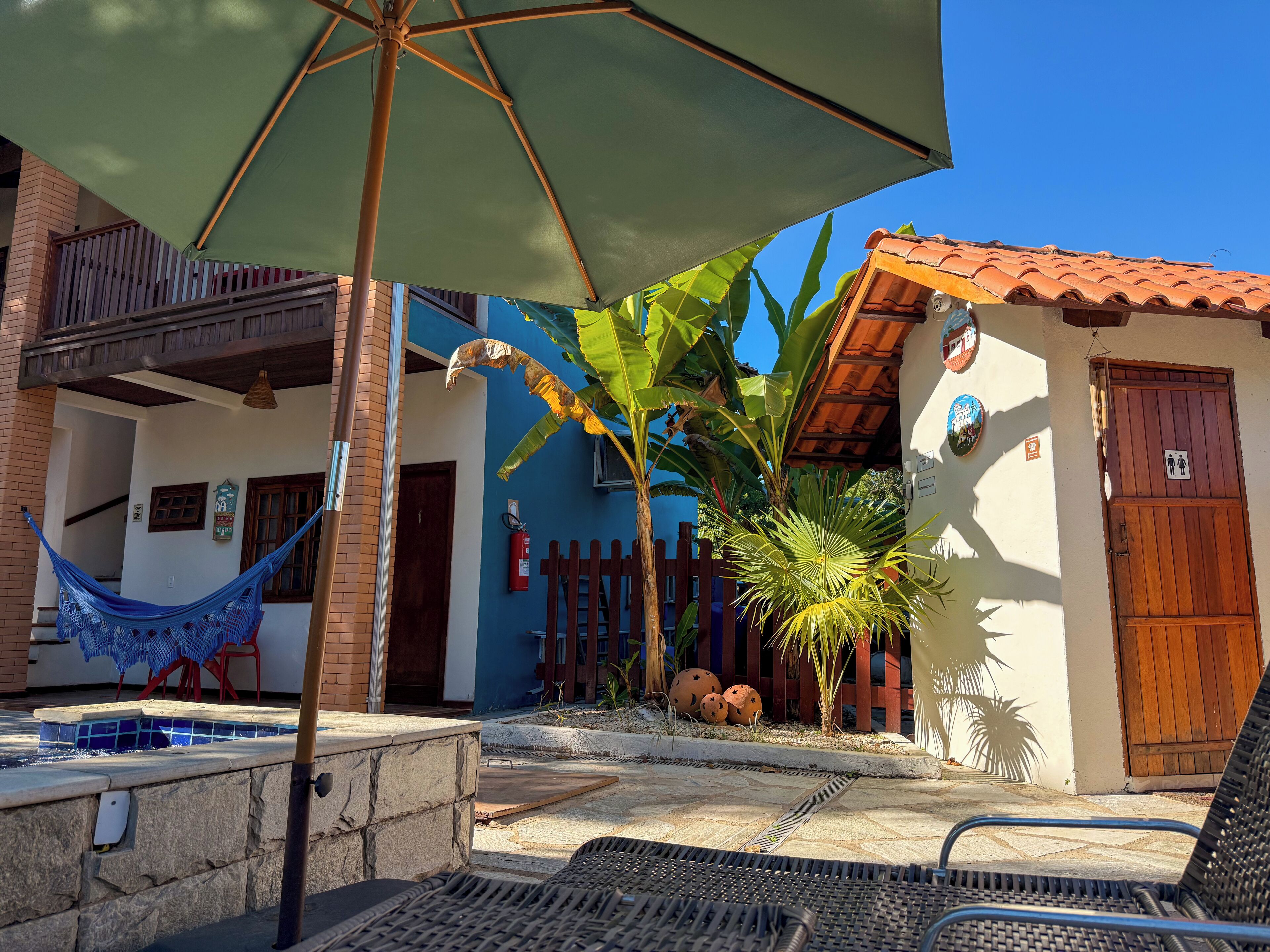 A pool area with a hammock, chairs, and a wooden door.