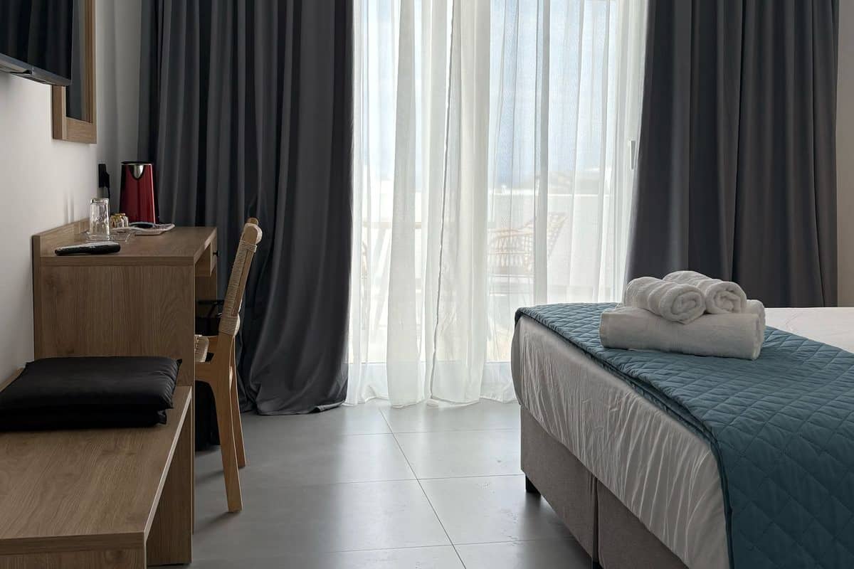 A hotel room with a bed, a desk, and a chair.