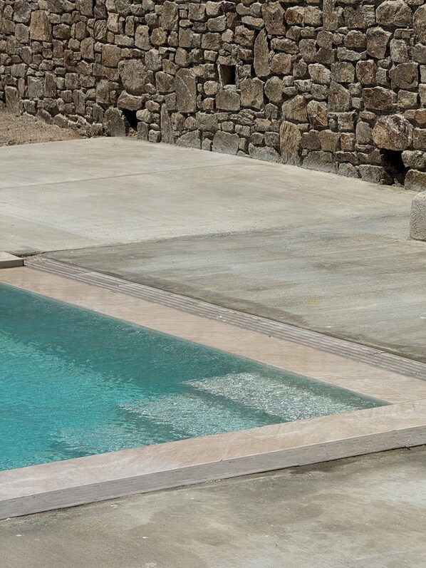 A swimming pool with a stone wall in the background. - The Blue of Mykonos (Mykonos)