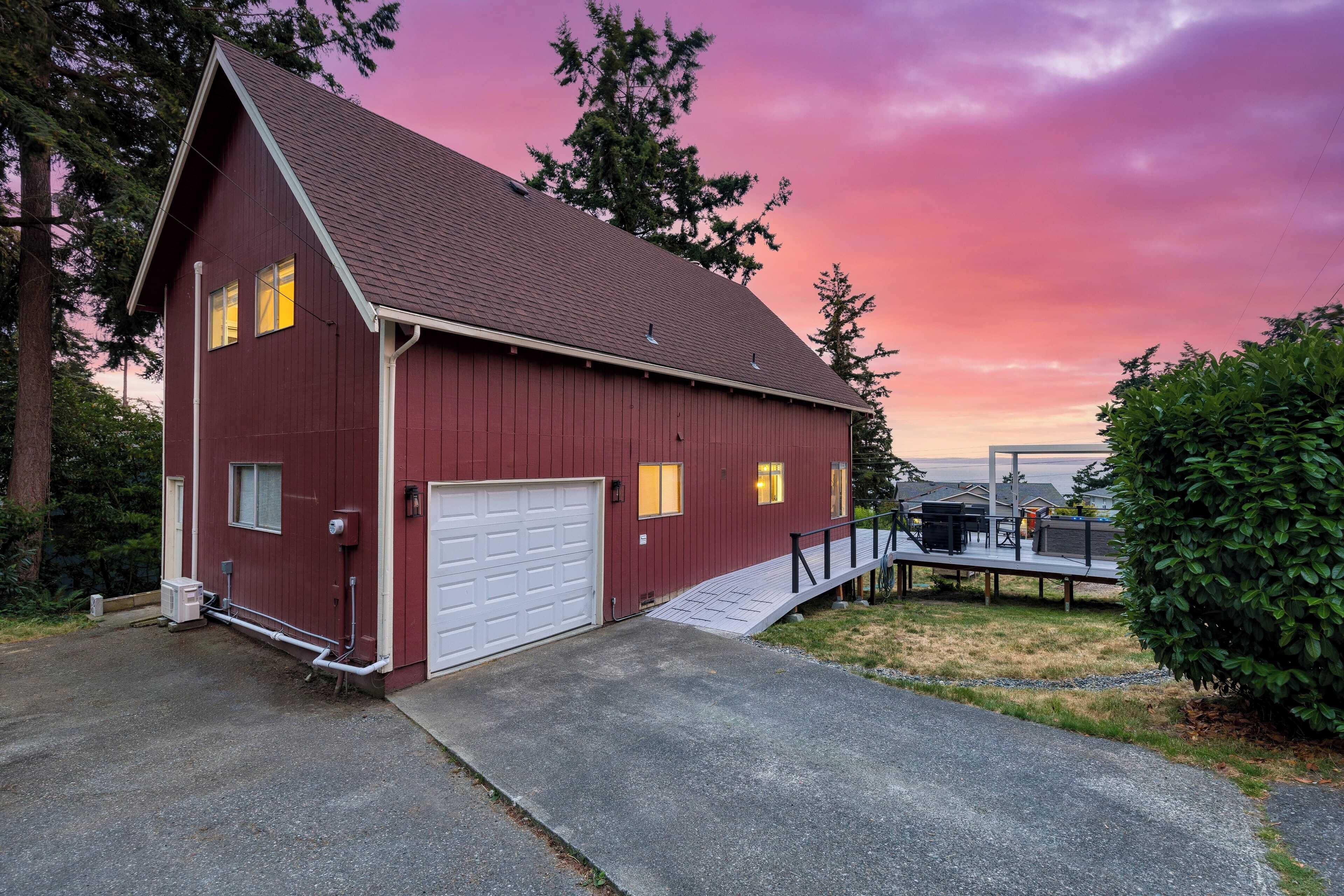 A red barn with a white garage door, a ramp, and a small outdoor seating area.