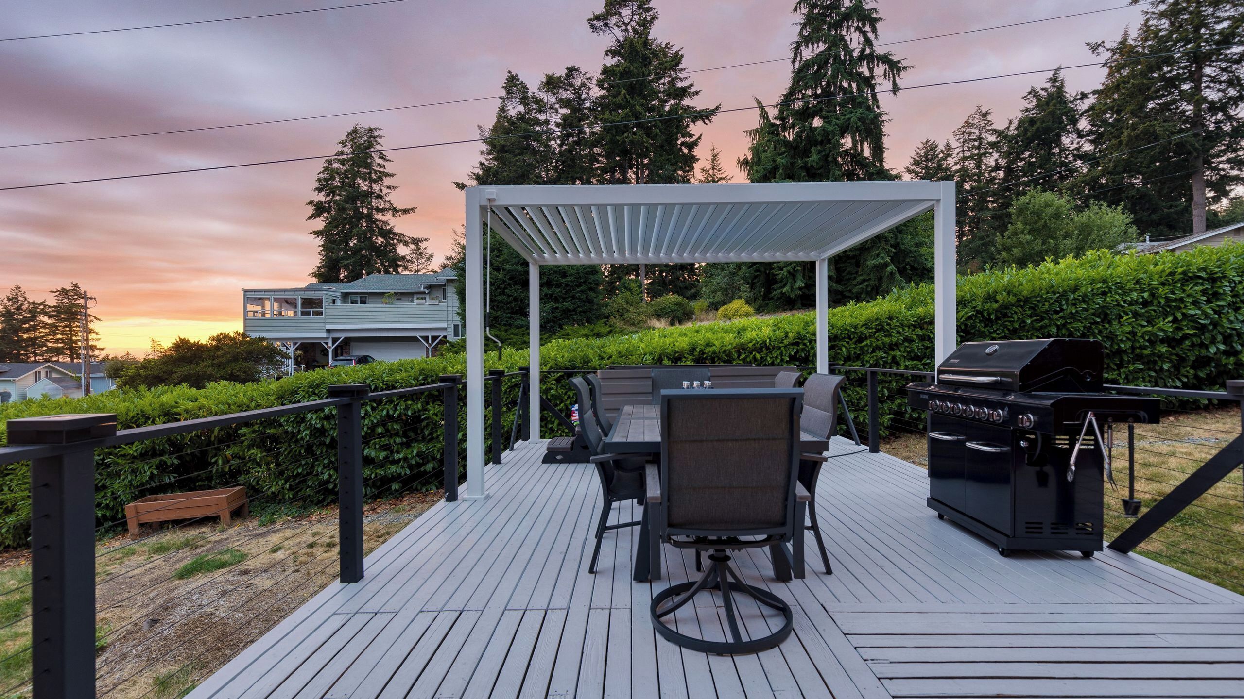 A deck with outdoor furniture, a grill, and a pergola.