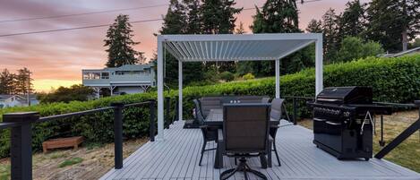 A deck with outdoor furniture, a grill, and a pergola.