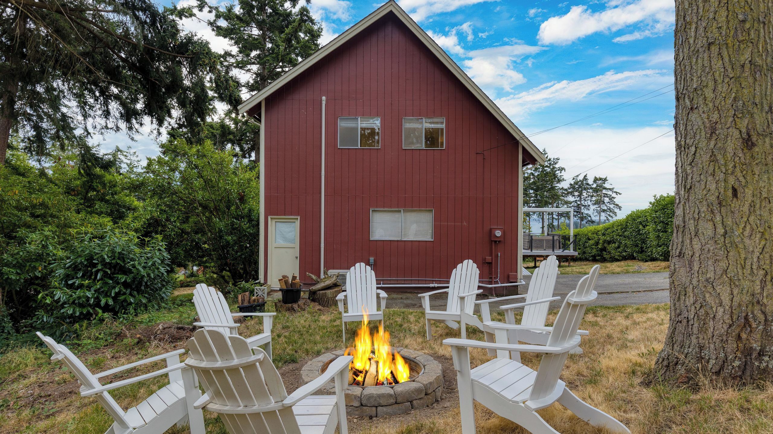 A red building with a fire pit and white chairs in front.