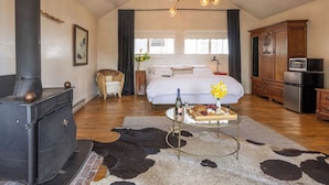 A cozy bedroom with a bed, a wooden dresser, a stove, and a cowhide rug.