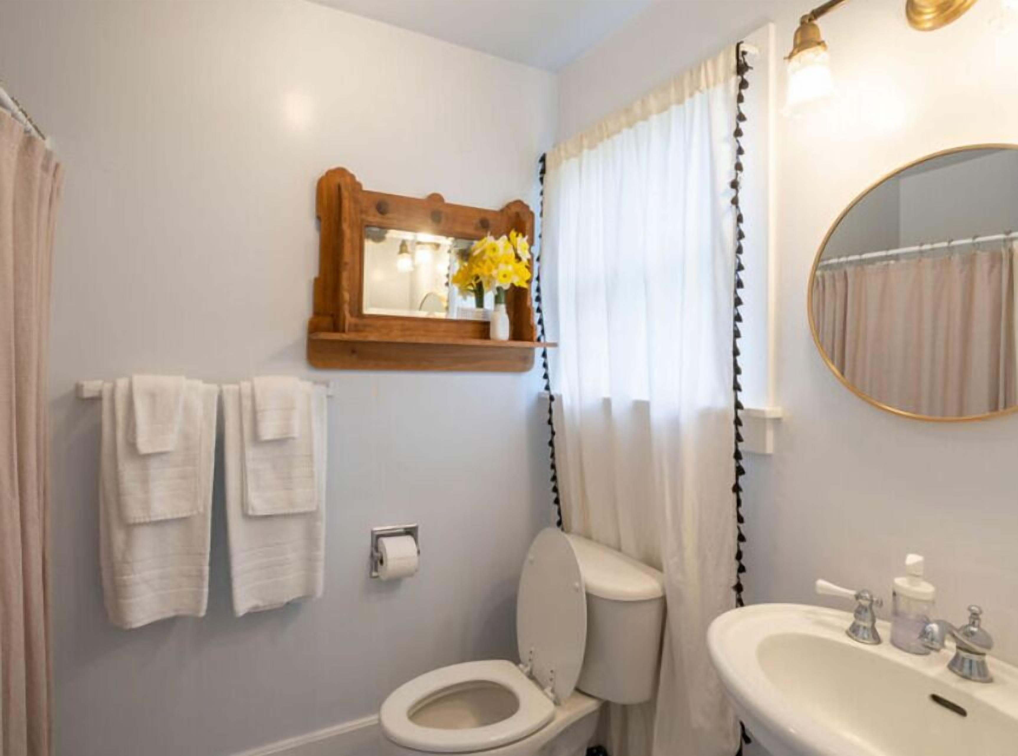 A bathroom with a toilet, sink, mirror, and towels.