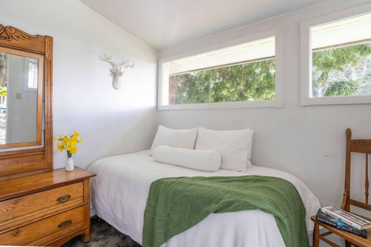 Un dormitorio con cama, cómoda, espejo y decoración de cabeza de ciervo.