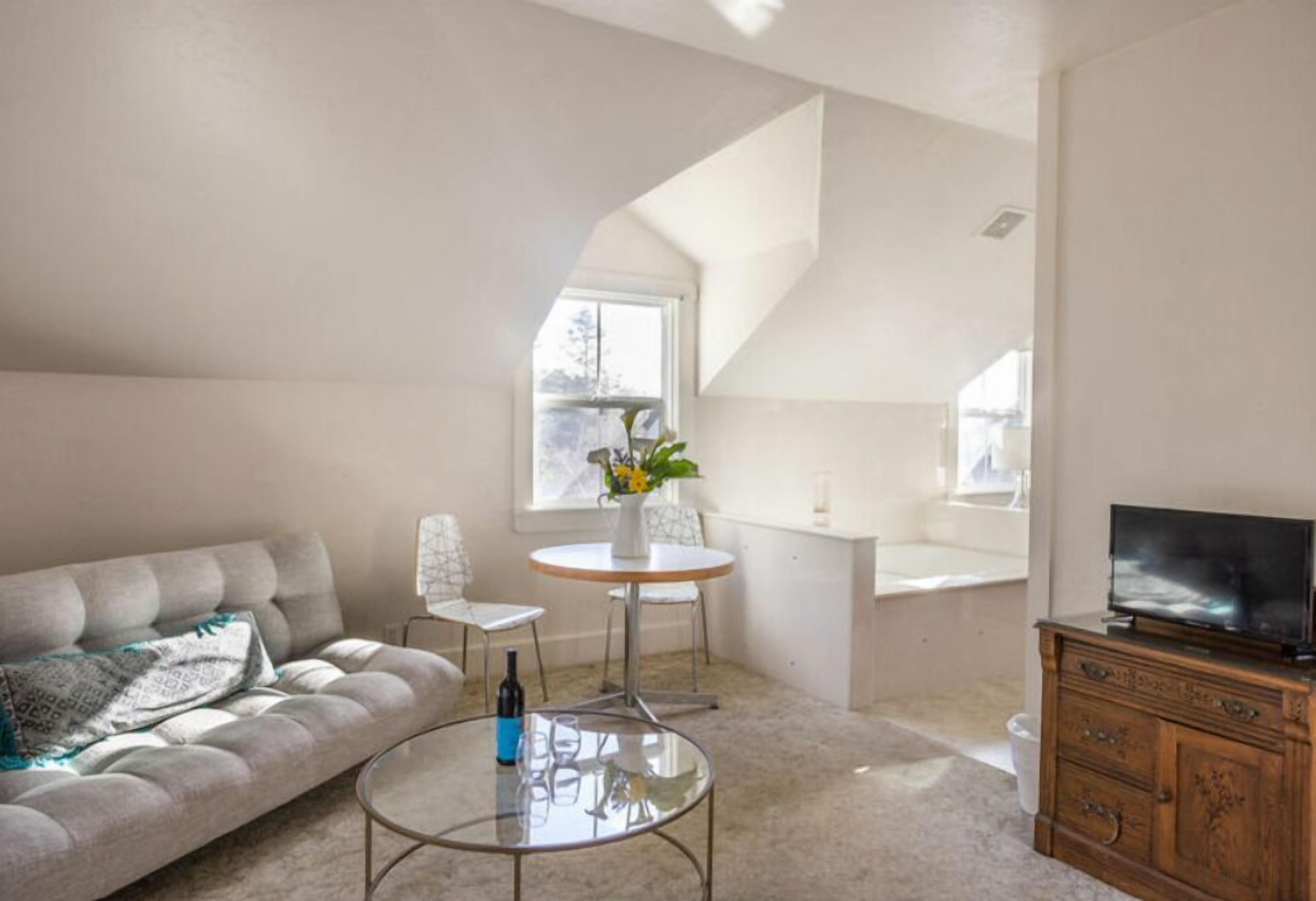 Ein modernes Wohnzimmer mit einer Couch, einem Glastisch, einem Fernseher und einem Essbereich mit Tisch und Stühlen.