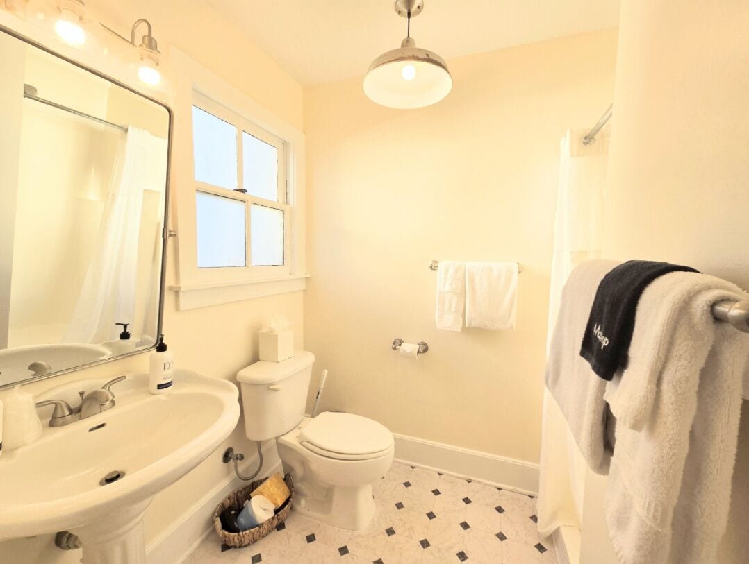 A bathroom with a sink, toilet, and mirror.
