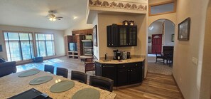 Un amplio salón con una gran mesa de comedor, una cocina con armarios oscuros y una chimenea.