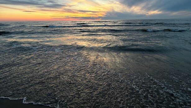 Una playa al atardecer con olas acariciando suavemente la orilla.