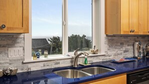 A kitchen with a large window, a stainless steel sink, and wooden cabinets. - Casa de Marea - 2BD Condo - Close to Beach +Garage (Lincoln City)