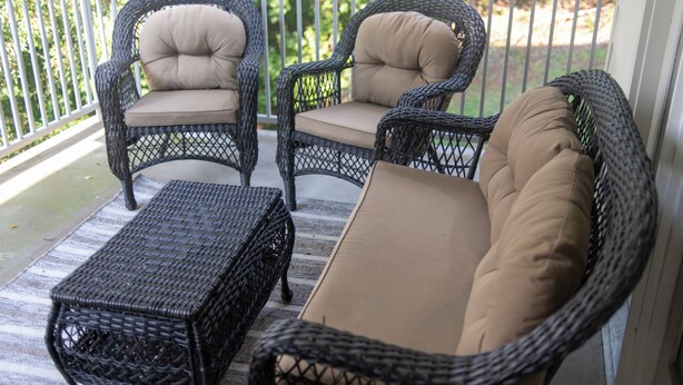A wicker outdoor seating area with cushioned chairs and a matching ottoman on a porch. - Peaceful Condo on Lake Marion in Santee, SC. Time to play golf and go fishing! (Santee)