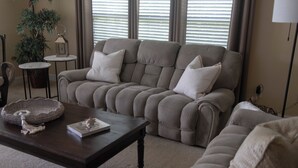 A living room with a beige sectional sofa, a dark wooden coffee table, a small side table with a lantern, and a potted plant. - Peaceful Condo on Lake Marion in Santee, SC. Time to play golf and go fishing! (Santee)