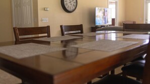 A dining area with a wooden table, chairs, and a wall-mounted clock. - Peaceful Condo on Lake Marion in Santee, SC. Time to play golf and go fishing! (Santee)