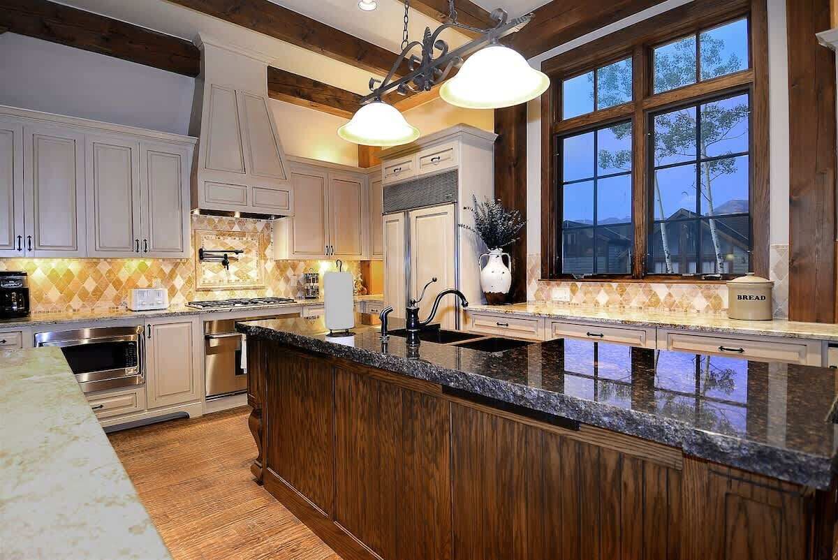 A kitchen with wooden cabinets, a granite countertop, stainless steel appliances, and a large window.