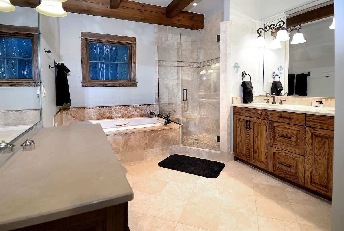 A bathroom with a bathtub, shower, vanity, and wooden cabinets.