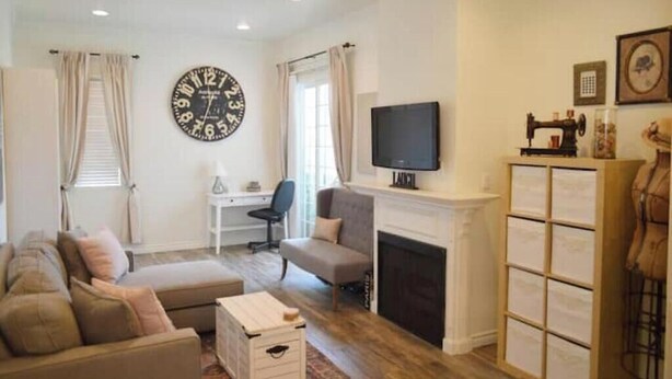 A living room with a sofa, a television, a fireplace, and a large wall clock.