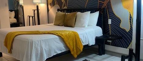 A bedroom with a bed, a large wall mural, a nightstand, a lamp, and a rug.