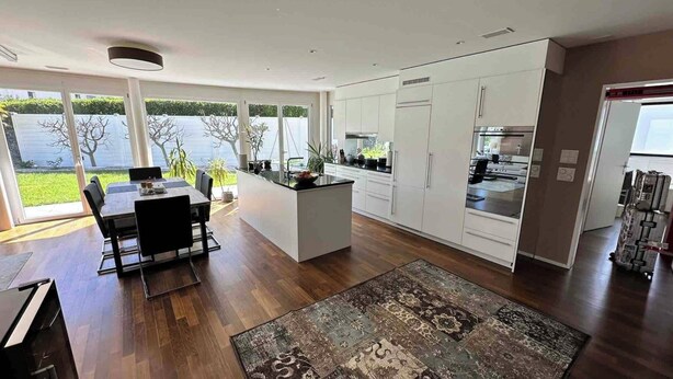 A modern kitchen with a central island, white cabinetry, and a view of a lake. - Garden apartment at Zurich lake (Richterswil)