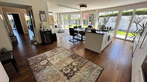 A spacious kitchen with a dining area, large windows, and a view of the outdoors. - Garden apartment at Zurich lake (Richterswil)