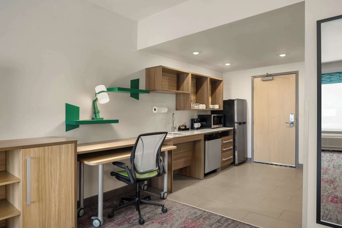A modern kitchen with wooden cabinets, a built-in microwave, and a refrigerator.