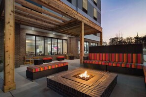 An outdoor seating area with a fire pit, wooden pergola, and modern furniture. - Home2 Suites By Hilton Conyers Atlanta (Conyers)