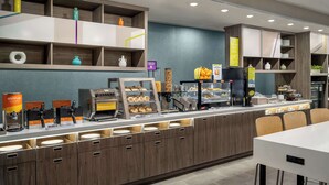 Una barra de desayuno moderna con diversas opciones de comida y una máquina de café.