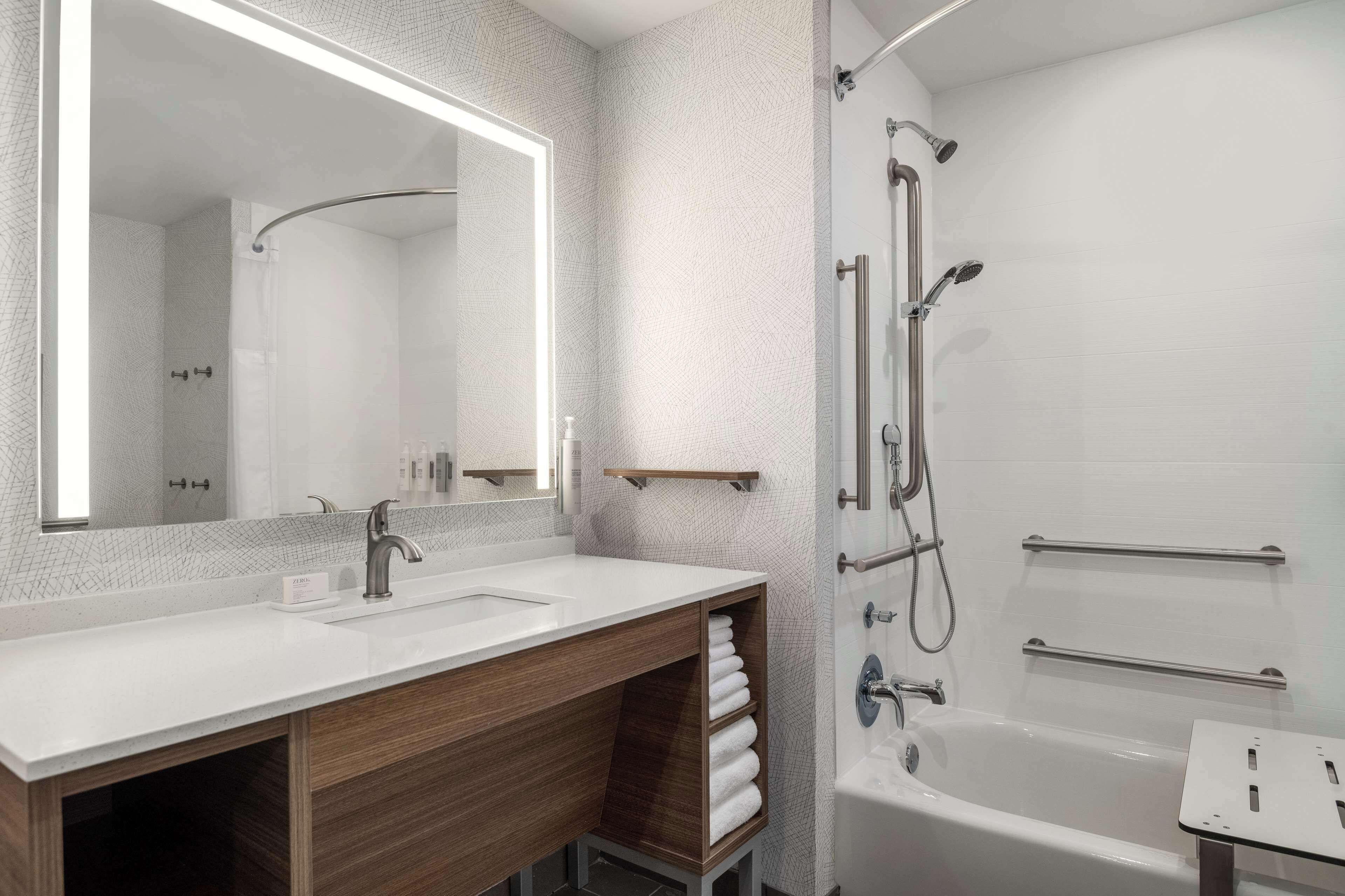 Een moderne badkamer met een grote spiegel, twee wastafels, een douche en een bad.