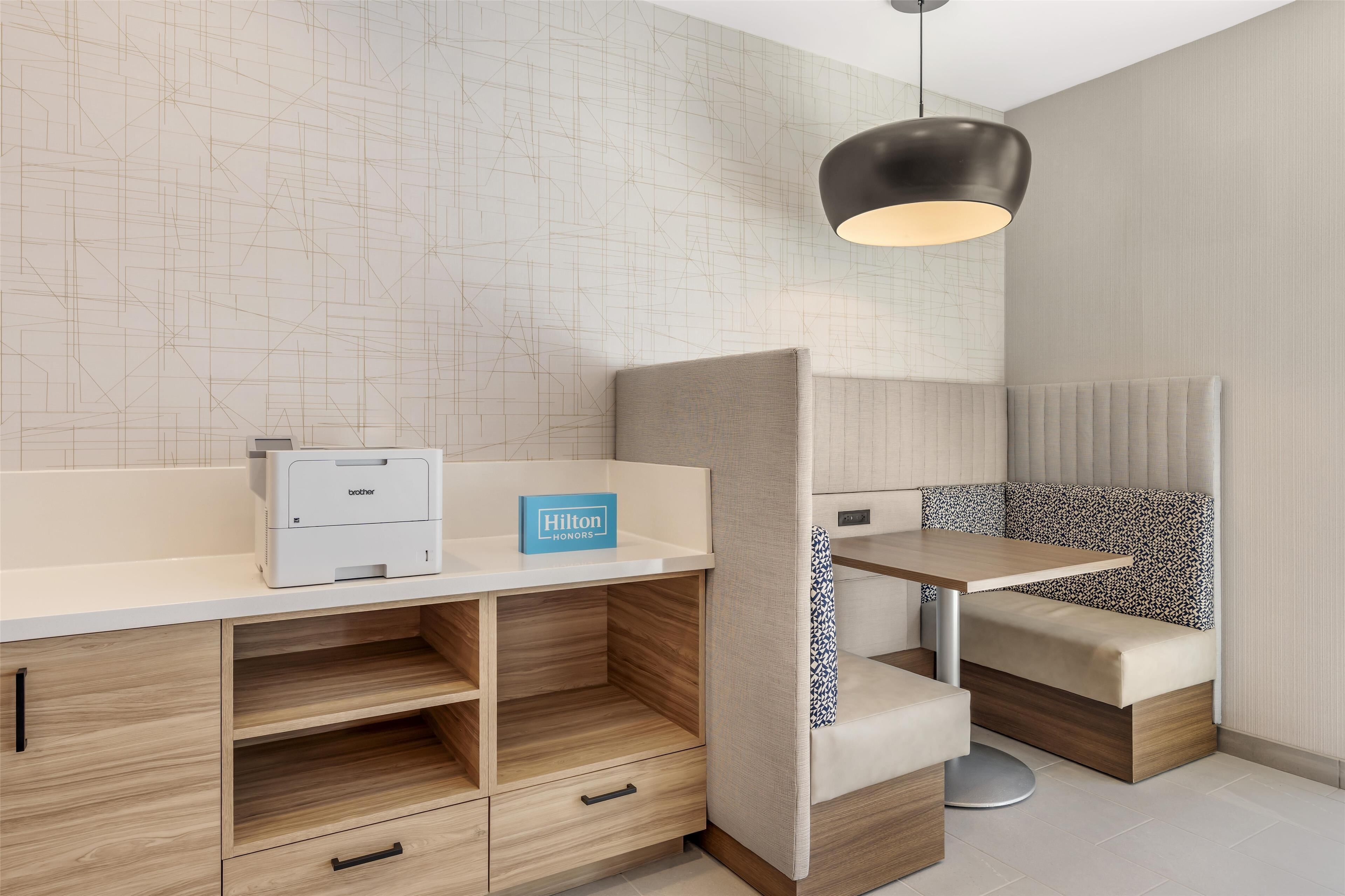 A modern hotel room with a minibar, a desk, and a seating area.