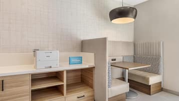 A modern hotel room with a minibar, a desk, and a seating area.