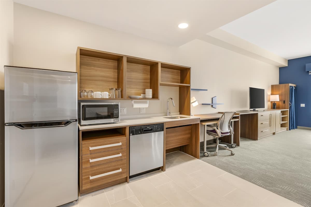 A modern kitchen with a refrigerator, microwave, dishwasher, and wooden cabinetry.