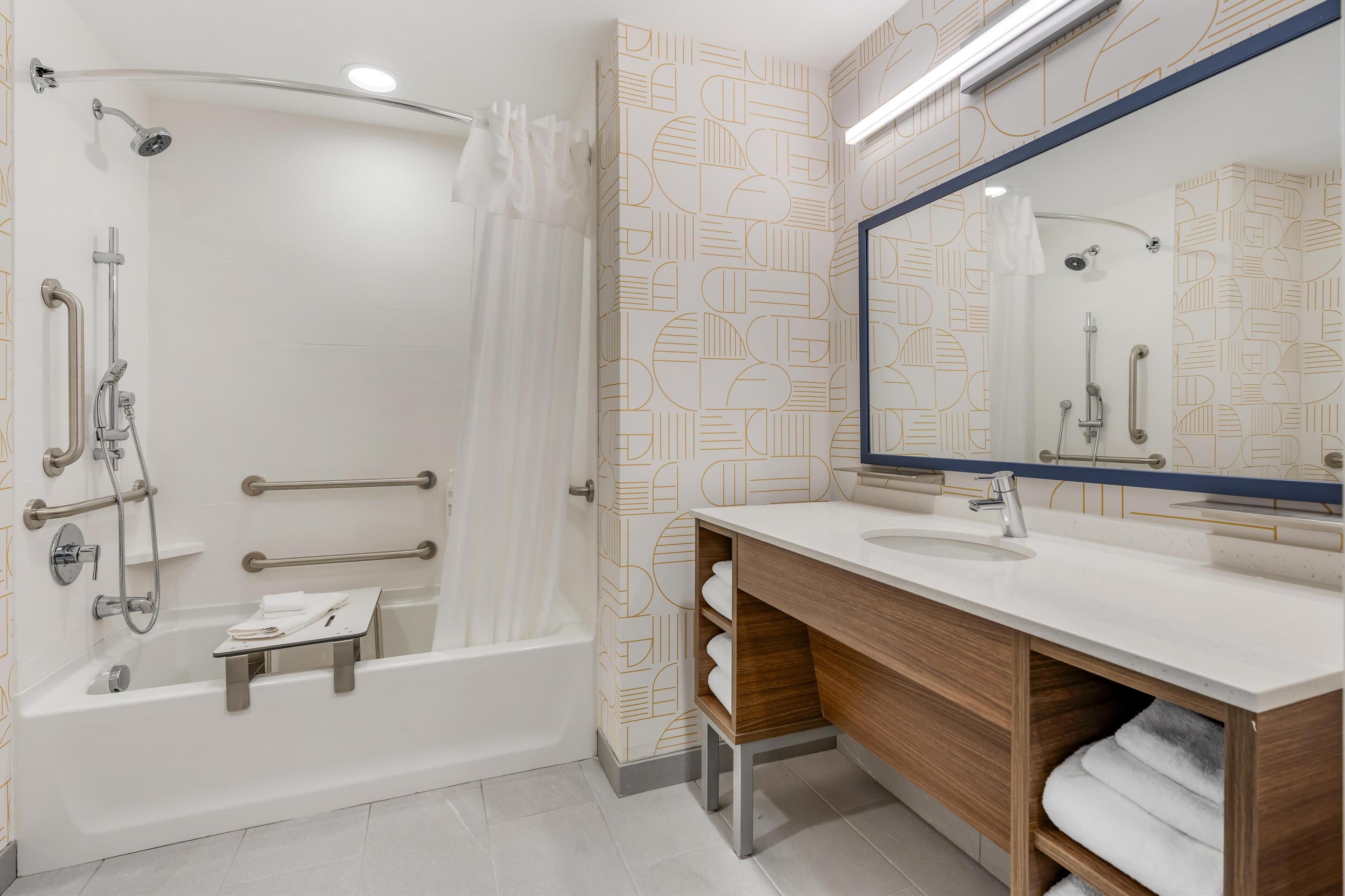A modern bathroom with a bathtub, shower, and vanity with a mirror.