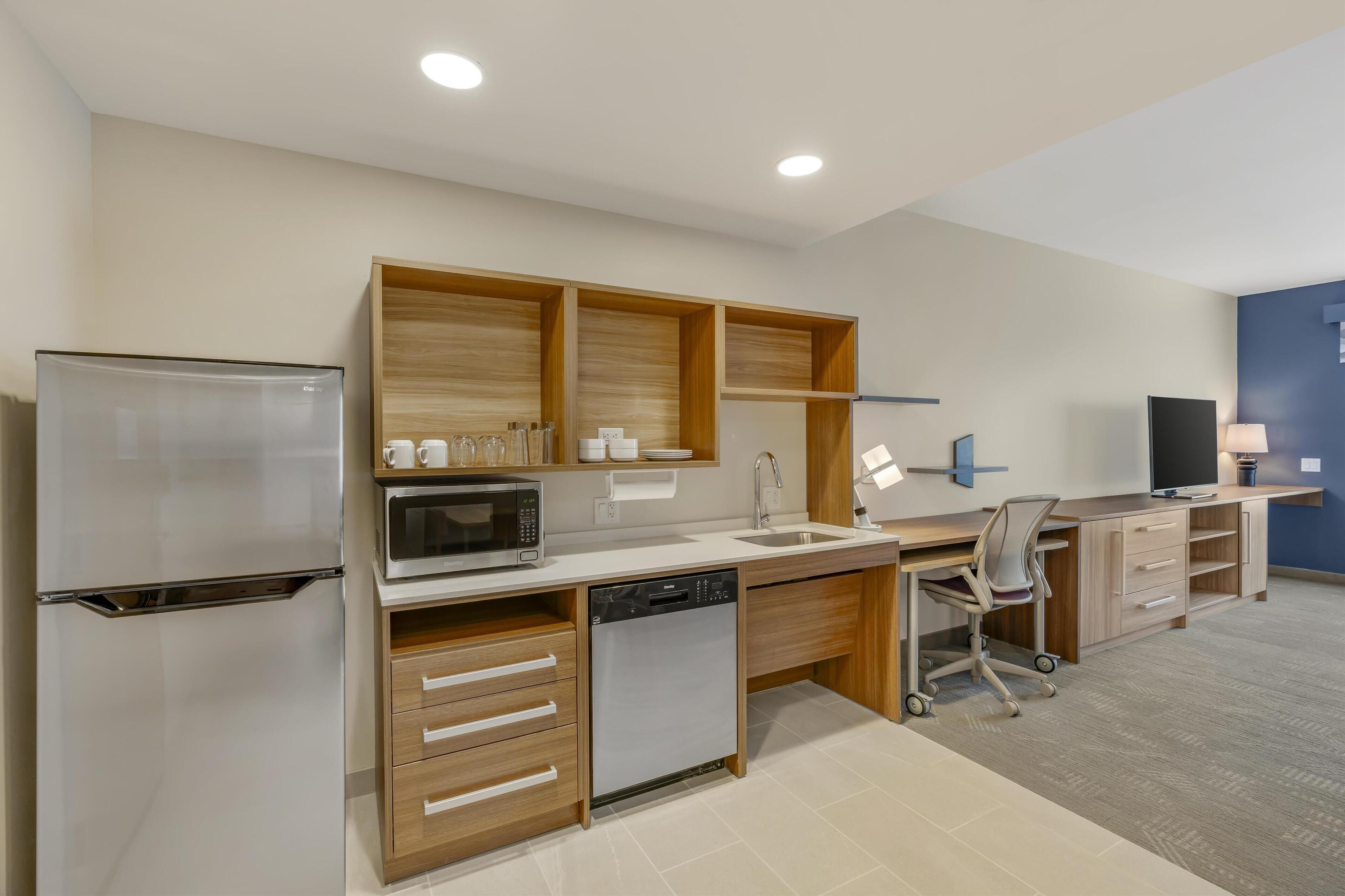 A modern kitchen with a refrigerator, microwave, dishwasher, and wooden cabinets.