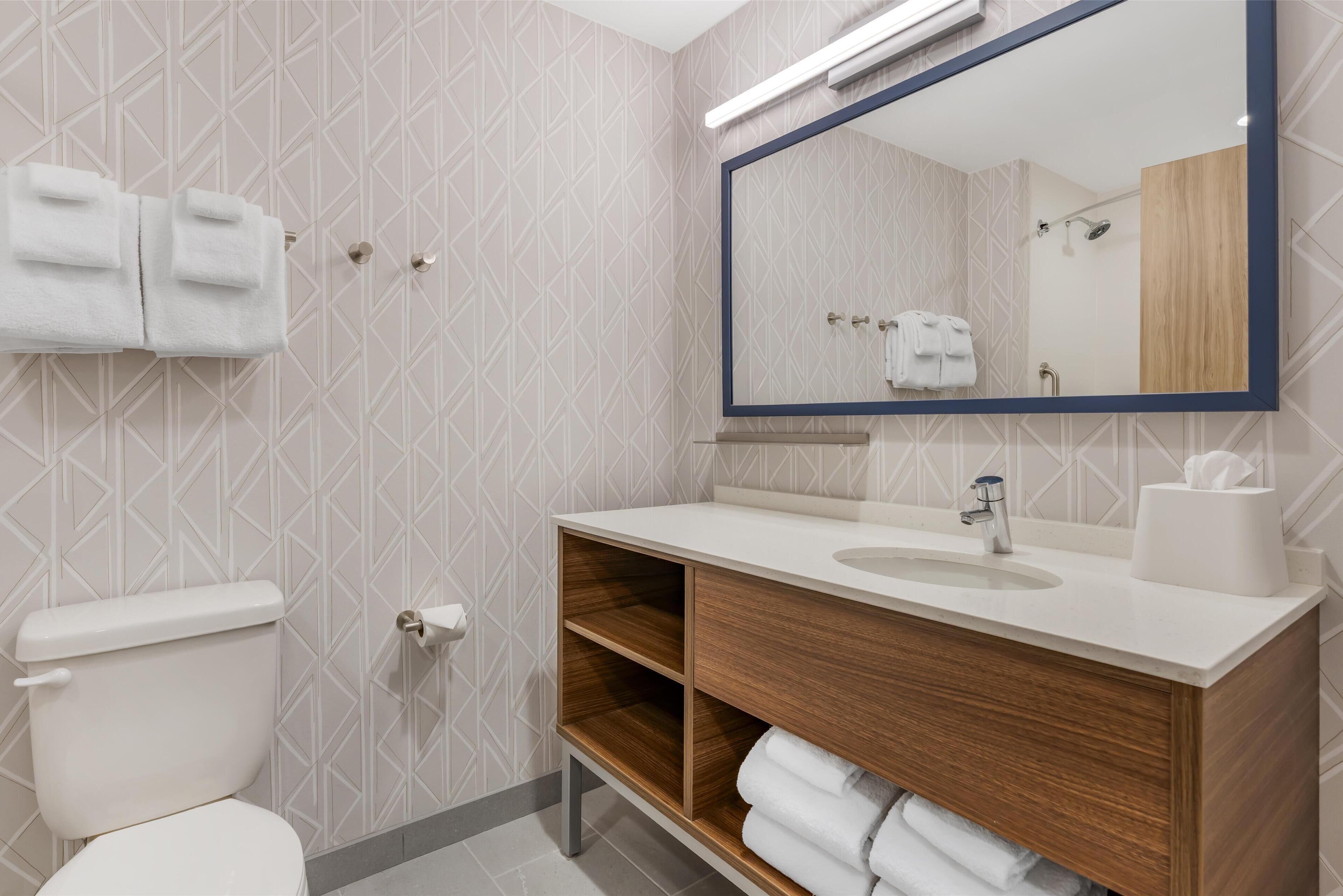 A modern bathroom with a toilet, sink, and mirror.