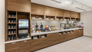 A buffet setup with a coffee machine, waffle maker, and various food items. - Home2 Suites By Hilton Bozeman Four Corners (Bozeman)