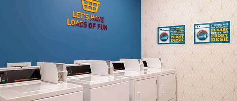 A laundry area with multiple washing machines and a blue wall with a motivational quote.