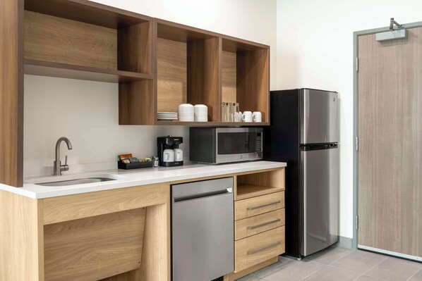 Una cocina moderna con armarios de madera, un refrigerador de acero inoxidable, un microondas y un lavavajillas.