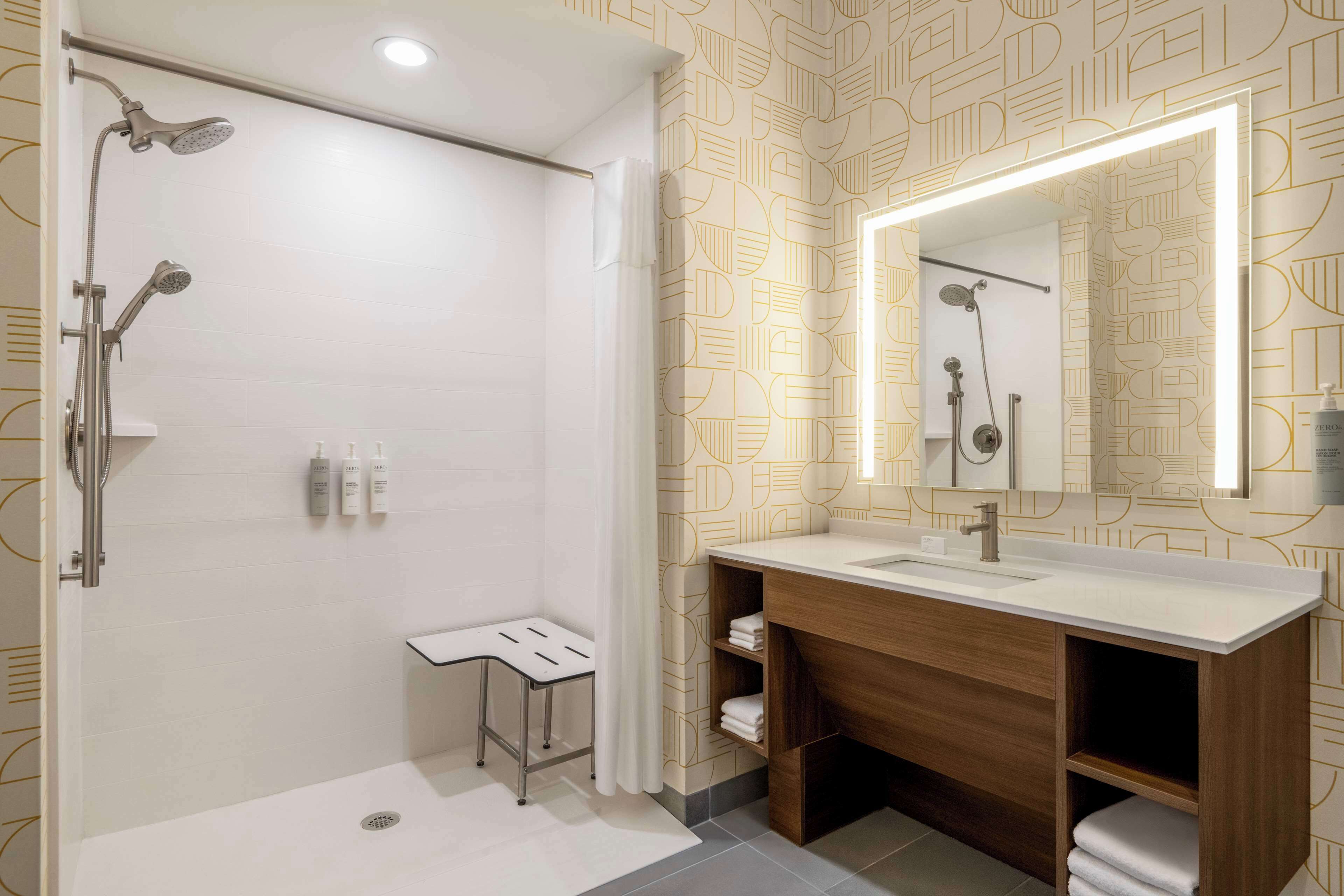 A modern bathroom with a shower, vanity, and a mirror.