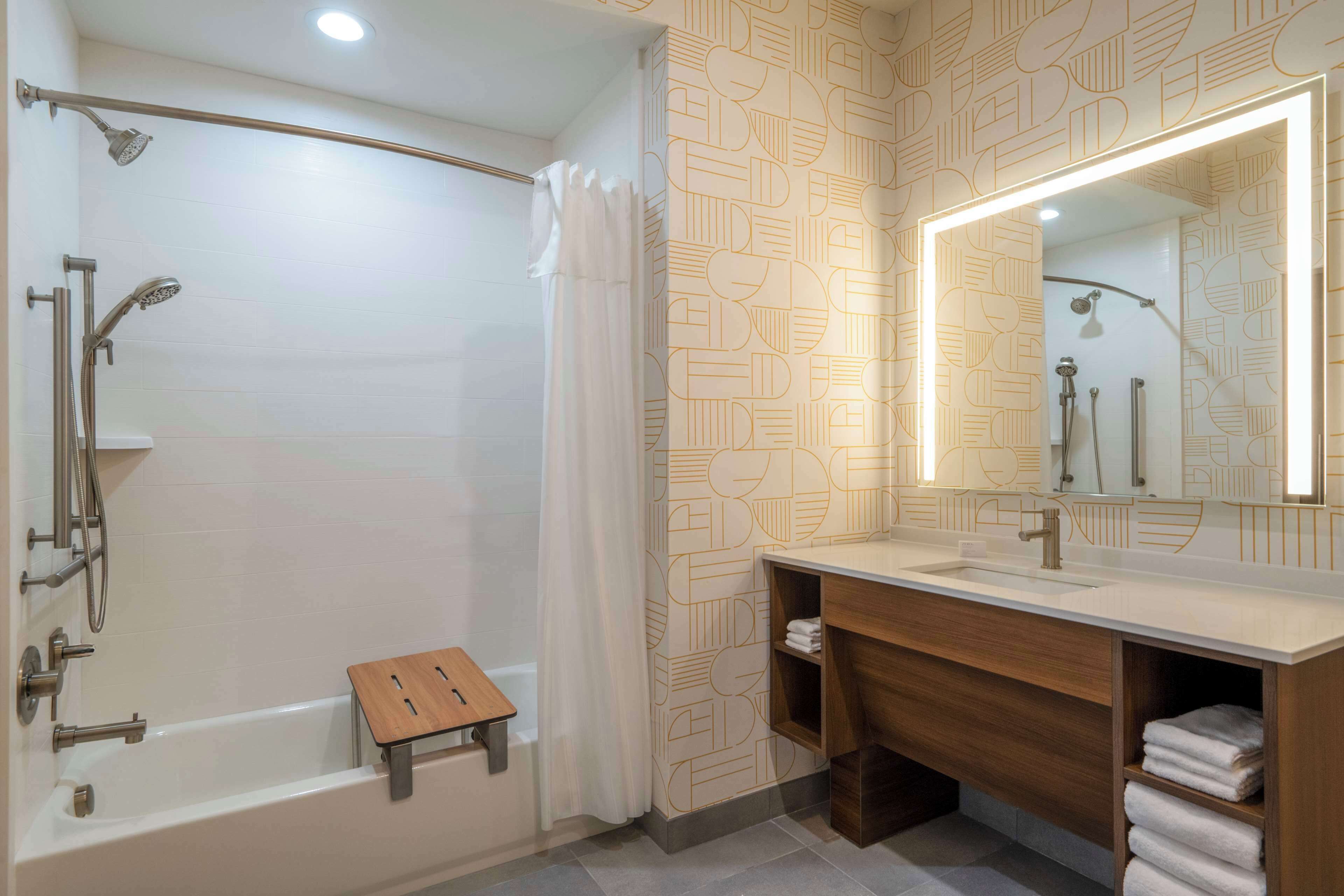 Une salle de bain moderne avec une baignoire, une douche, un meuble-lavabo et un grand miroir.