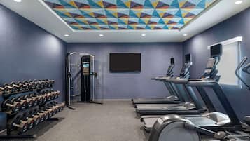 A gym with treadmills, dumbbells, and a weight machine.