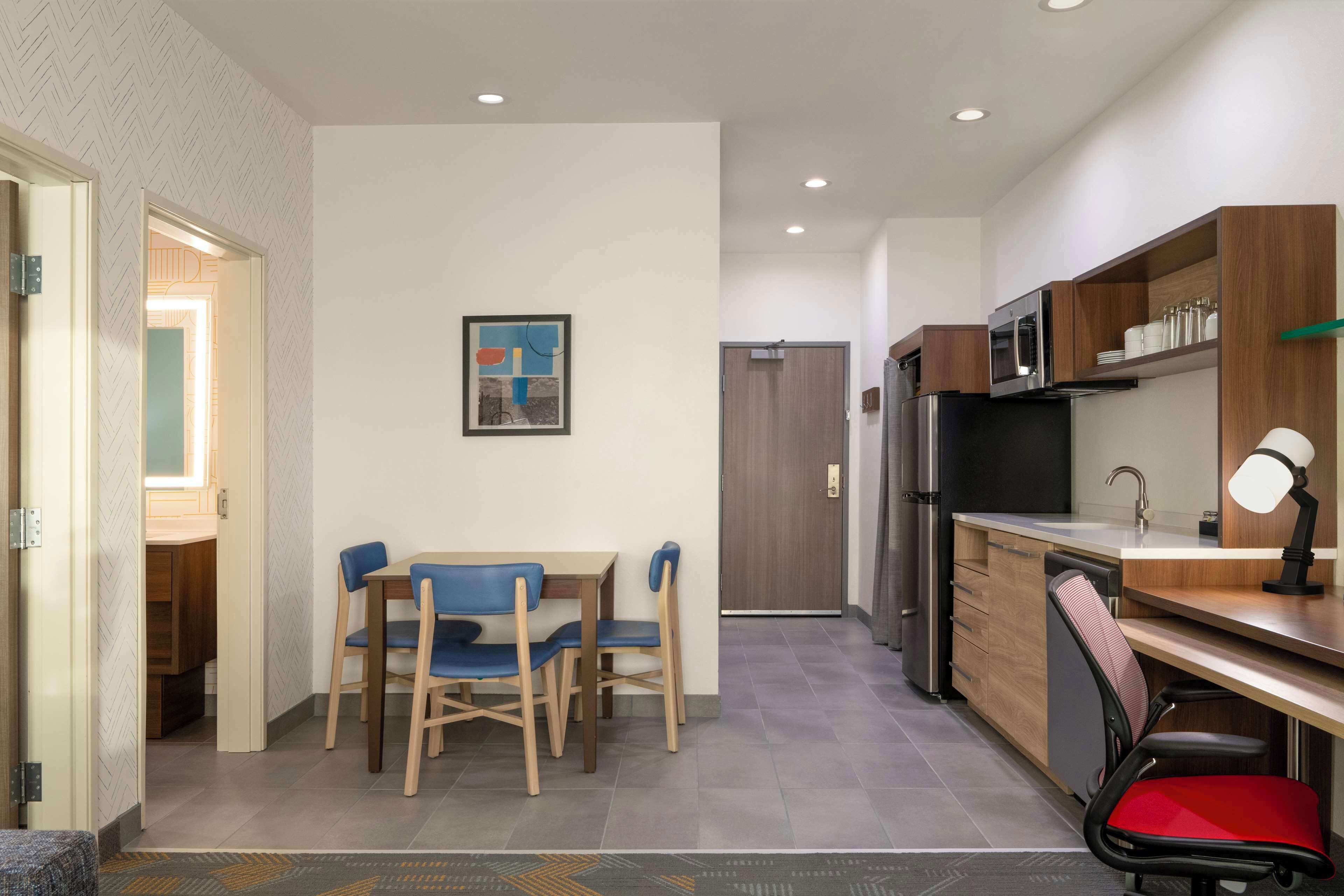 A compact kitchen with a dining area, a refrigerator, a microwave, and a sink.