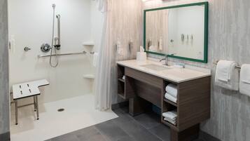 Un baño moderno con ducha, lavamanos, espejo y toallero.