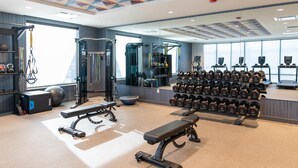 A modern gym with various exercise equipment, including dumbbells, benches, and a squat rack. - Home2 Suites By Hilton Effingham (Effingham)
