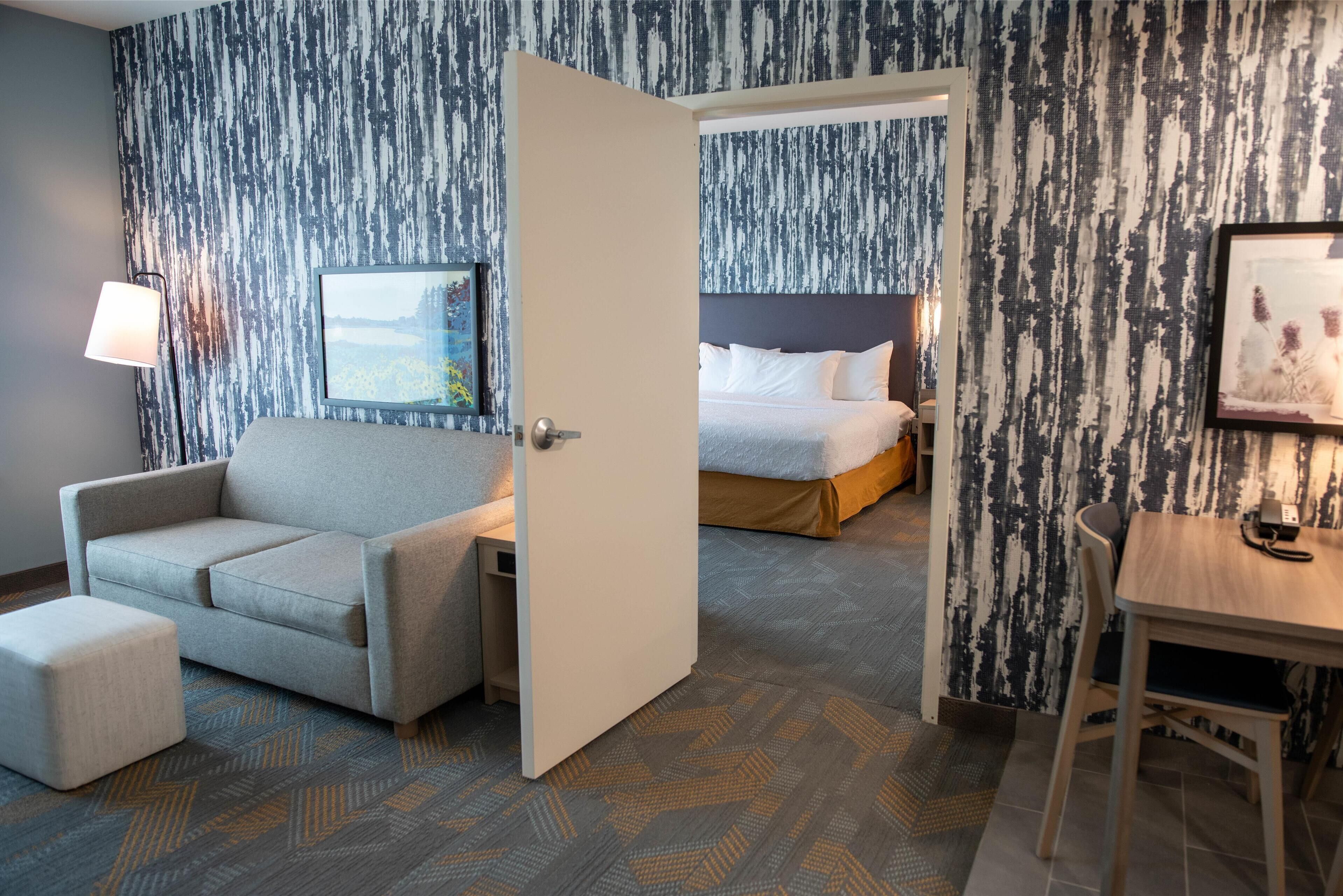 Et hotelværelse med sofa, et lille bord, en seng og et billede på væggen.