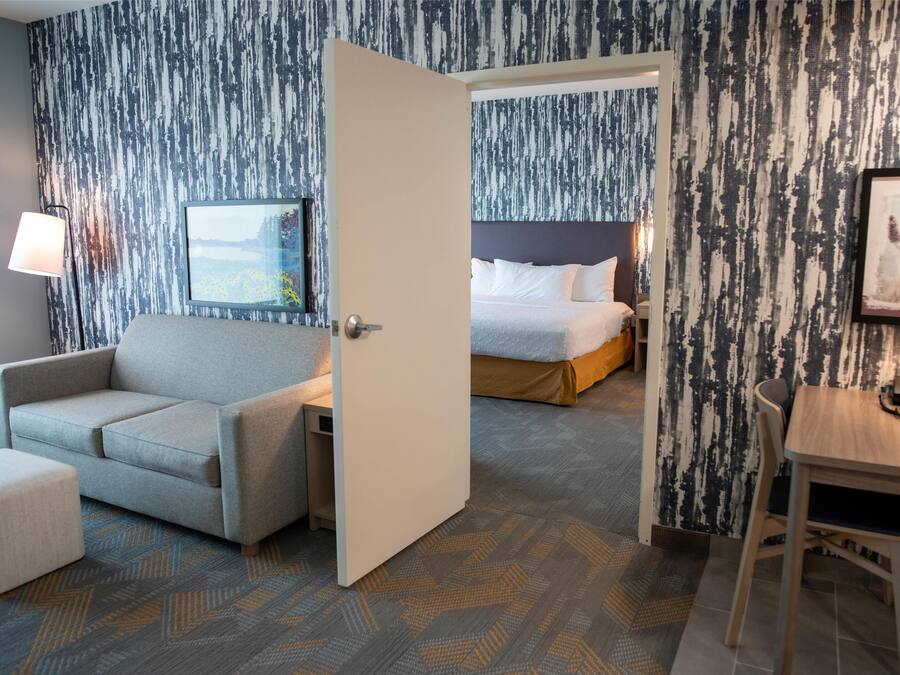 Ein Hotelzimmer mit Sofa, einem kleinen Tisch, einem Bett und einem Bild an der Wand.