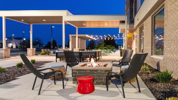 An outdoor patio area with a fire pit, seating, and a covered section. - Home2 Suites By Hilton Effingham (Effingham)