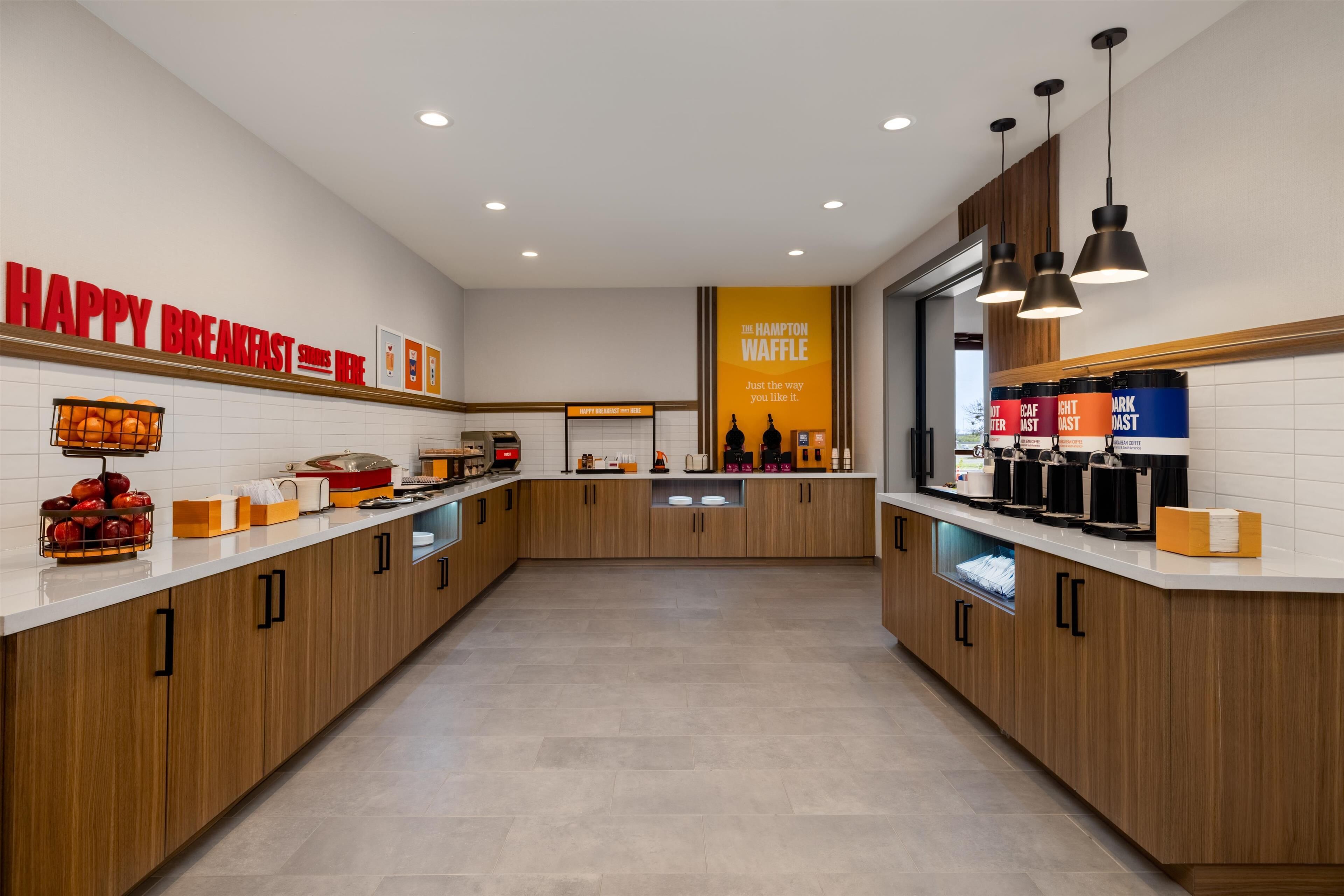 A modern kitchen with wooden cabinets, a breakfast bar, and a sign for The Hampton Waffle.