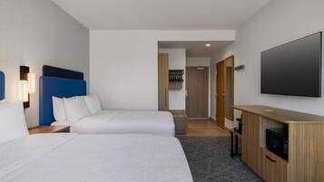 Een hotelkamer met twee bedden, een televisie, een magnetron en een houten kast.