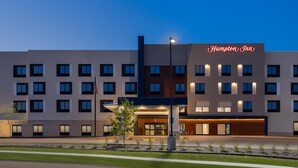 A Hampton Inn hotel with a modern facade, multiple floors, and a well-lit entrance.